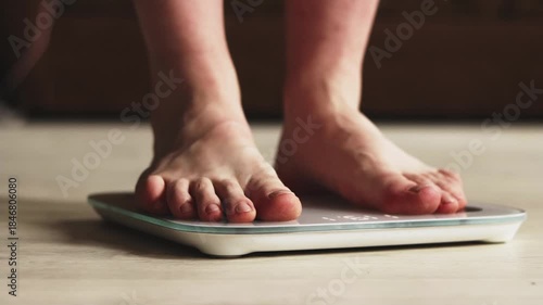 Close-up of male feet on a digital bathroom scale on a wooden floor.