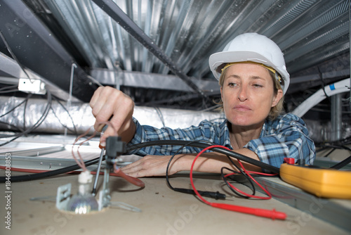 female electrician fixing ceiling lighting