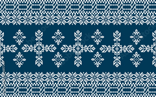 Traditional Nordic knitting pattern featuring symmetrical geometric shapes in white on a dark blue background.