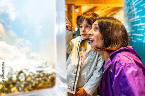 Obraz na płótnie Mother and child observing fish tank at aquarium