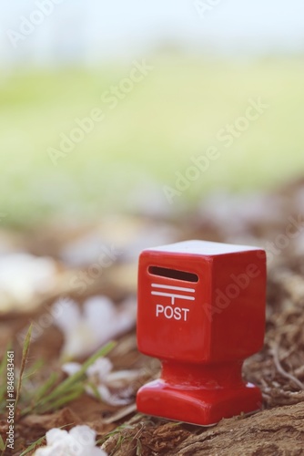 Red mailbox with pink flower fall on ground nature background