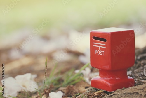 Red mailbox with pink flower fall on ground nature background