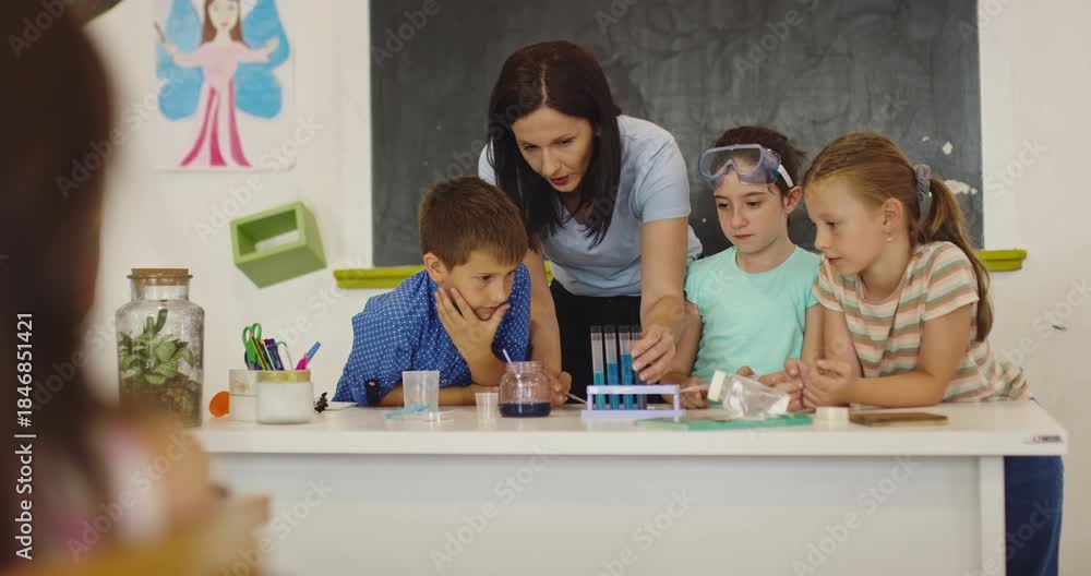 Female teacher guiding focused elementary students through a hands-on ...