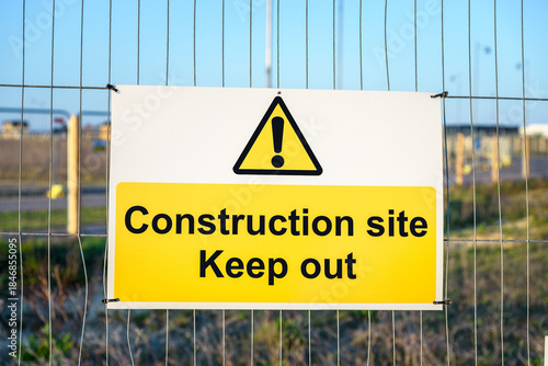 Keep out sign on a metal fence at a construction site at sunset