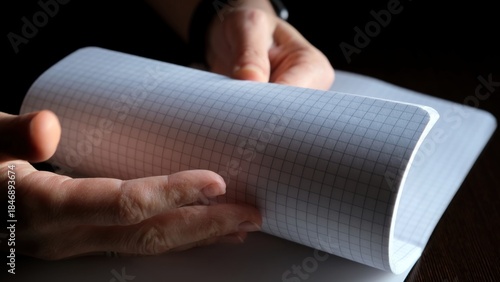 Female hands Flipping new notebook pages. Fast flicking of paper checkered sheets. View browsing. Search of note. Pleasant tactile sensations and stress relief. High quality photo.
