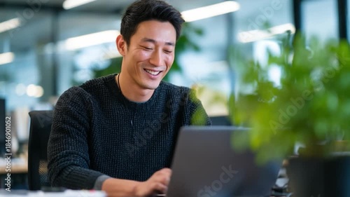 Asian male solar firmware engineer smiling while updating controller software on laptop.