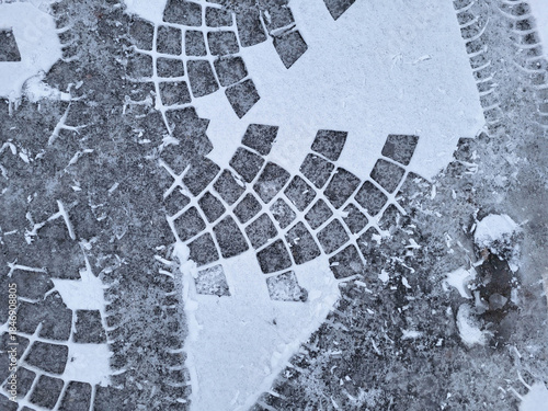 Fresh tire tracks on the white snow on the asphalt.