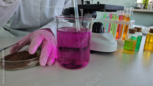 Scientist conducts chemistry experiment with colorful liquids and glassware in laboratory