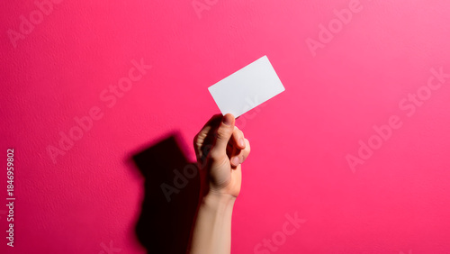 Hand holding blank white card on pink background