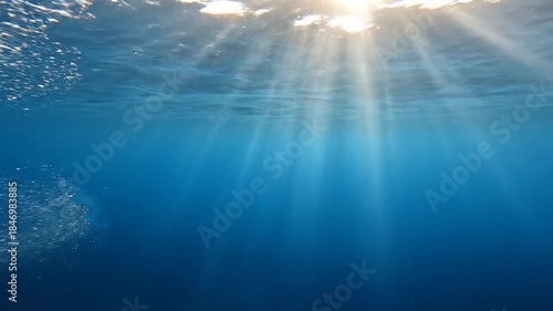 Underwater Scene With Sun Rays Shining Through Blue Water And Bubbles Rising Upward in Ocean Deep With Light Beams Through The Surface