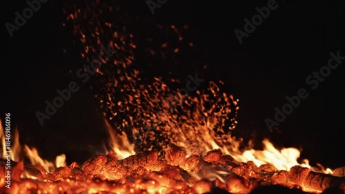 Close Up Of Burning Embers And Glowing Hot Coals With Orange Flames And Flying Sparks Against A Dark Background
