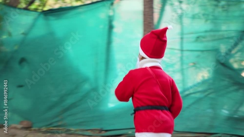cute toddler dressed as santa claus running outdoors