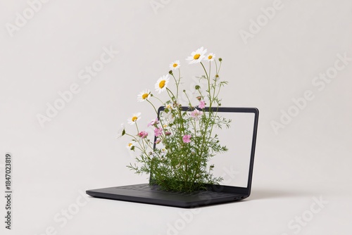Flowers are sprouting from an open laptop, creating a unique blend of nature and technology