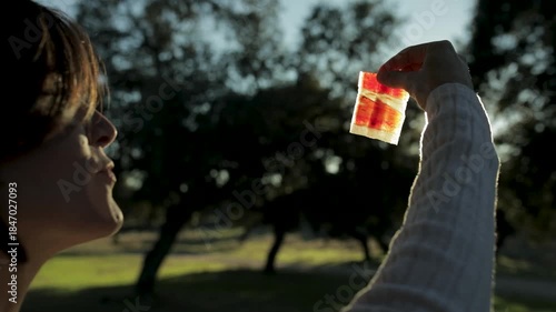 Mujer comiendo jamón ibérico al atardecer con la loncha expuesta al sol