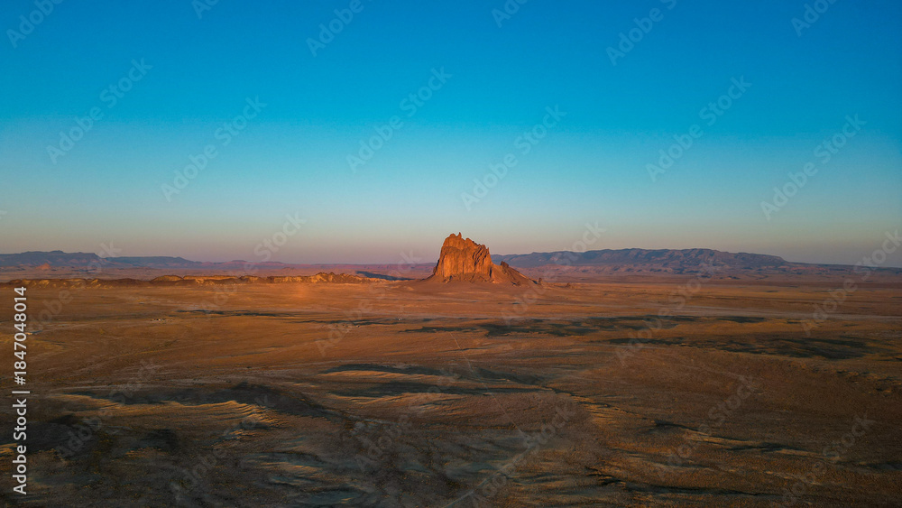 Naklejka premium A large rock sits in the middle of a vast, empty desert