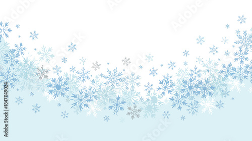 Snowflakes falling gently on winter background with soft blue gradient