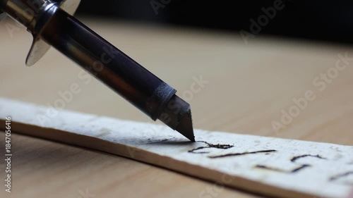 Close up of tool burning wood, pyrographic New Years text 2025/26