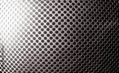 Primer plano de superficie oscura perforada con orificios circulares uniformes y reflejos brillantes sutiles.Rejilla de frontal de altavoz