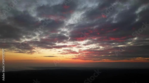 Orange sunset over vast horizon captured from drone, aerial panoramic landscape with glowing clouds, warm sky gradient and tranquil evening atmosphere, cinematic nature background