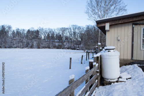 Tableau sur toile A silent snowy field and propane tanks by the fence and barn