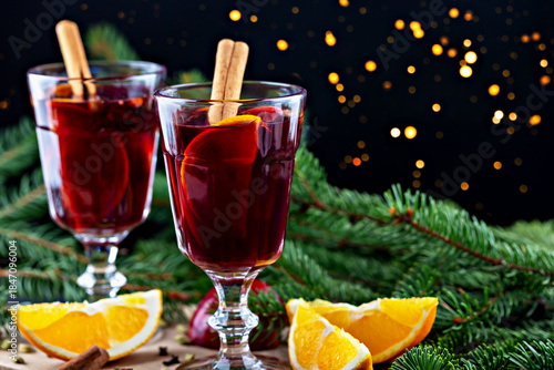 Mulled wine. Festive mulled wine served in elegant glasses, garnished with cinnamon sticks and orange slices, surrounded by fresh pine branches, creating warm and inviting holiday atmosphere