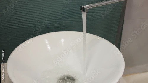 Water flows from the faucet in the bathroom. Close-up of the faucet and sink.