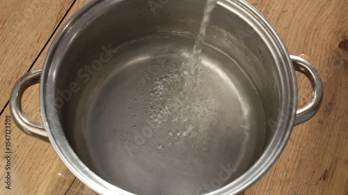 clean water is poured into a saucepan for further cooking of liquid food