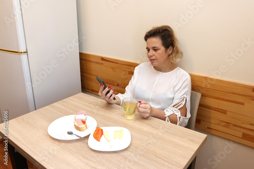 Woman drinking tea and eating sandwiches while sitting at the table