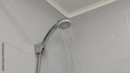 A close-up of a shower head with water flowing in a bathroom
