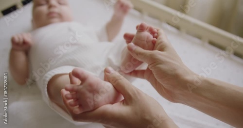 Mom female touching adorable newborn legs and massaging toes. Baby feet in mother hands. Happy Family concept. Baby foots close-up. Mother enjoying motherhood checks baby health. Feet heart shape.