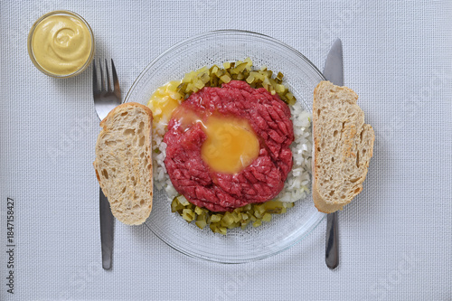 Fresh beef tartar, dish on a plate on a light background, flat lay