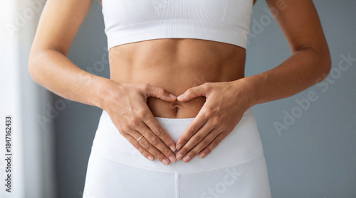 Woman showing heart gesture on her abdomen to symbolize wellness, gut health, and a balanced lifestyle.