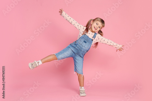 Canvas-taulu Happy little girl in jumpsuit having fun on pink background