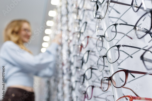 Canvastavla Eyeglass frames on optical store display with customer browsing in background