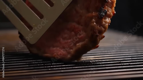 Burger patty sizzling on hot grill grates with char marks and rising steam, close-up shot evoking backyard barbecue, summer cookout, juicy grilled meat aroma