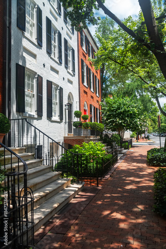 Quadro su tela Traditional Georgetown brick row houses with black shutters and greenery in Wash