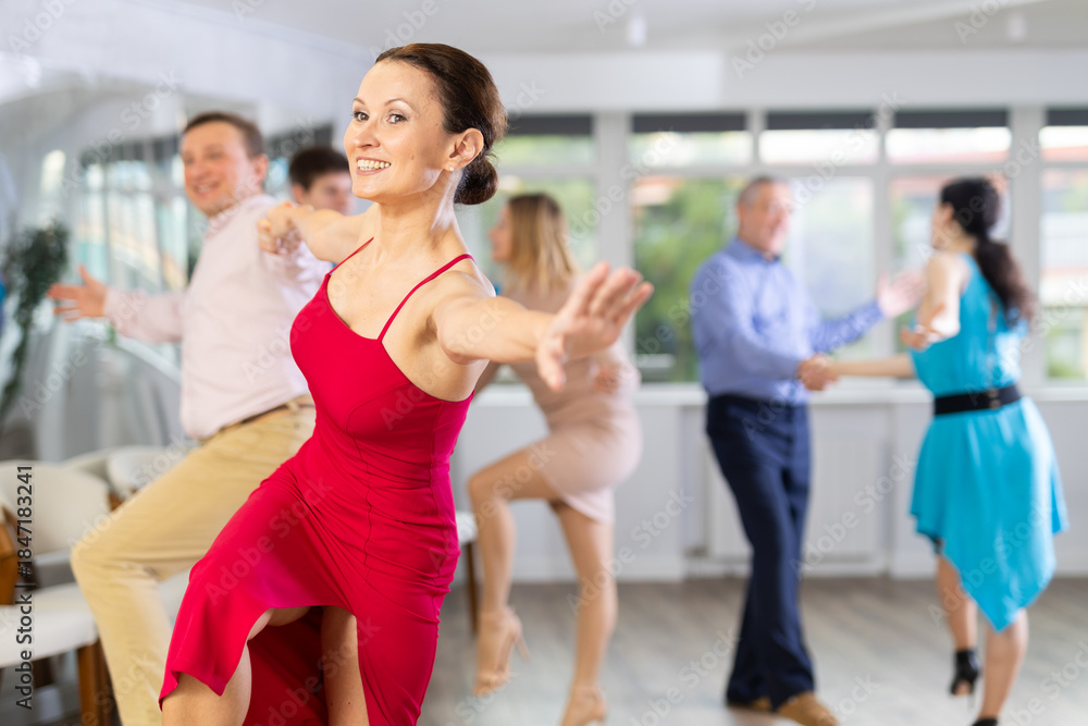 Fototapeta premium Positive men and women in party clothes enjoying jive in dance class