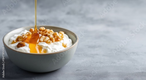 Greek yogurt bowl with honey and walnuts on gray background for healthy breakfast and dessert recipes food photography and culinary concepts