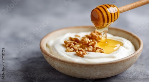 Greek yogurt bowl with honey and walnuts on gray background healthy breakfast food with natural sweetener and nutritious topping for diet