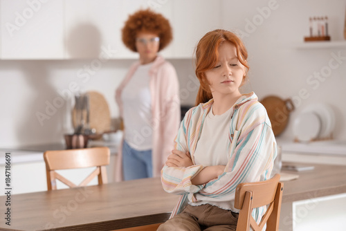 Upset teenage girl with her mother squabbling in kitchen