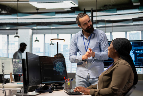 Pleased tech company manager applauding female programmer for optimizing code using AI. Satisfied team leader offering positive feedback to work done by african american woman in office