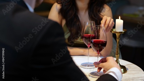 Happy romantic couple sitting in the restaurant, having date and holding glasses with red wine. Lifestyle, love, relationships concept.