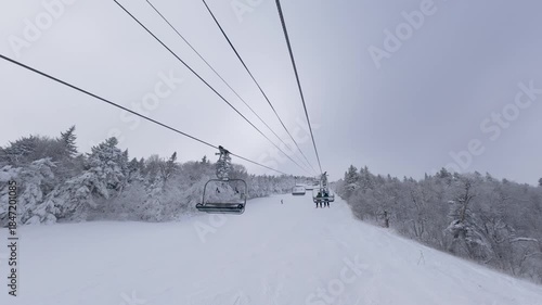 Ski chairlift at Killington Mountain, Vermont. Riding a lift in winter while snow skiing and snowboarding with white snowy trees and mountains. 4K video.