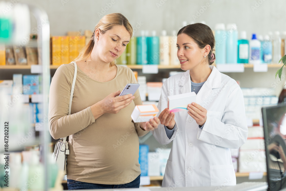Obraz premium Pregnant woman in pharmacy scans QR code on omega 3 supplement, worker offer similar item, advices European brand. Preparation for childbirth. Health care, healthy lifestyle, prevention