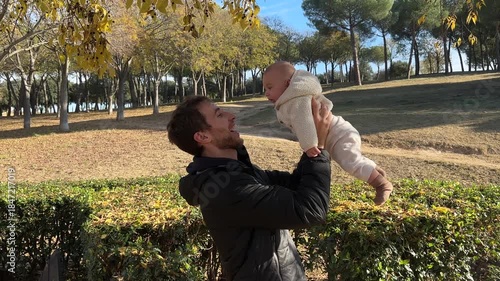 Affectionate father holding and kissing newborn baby in park