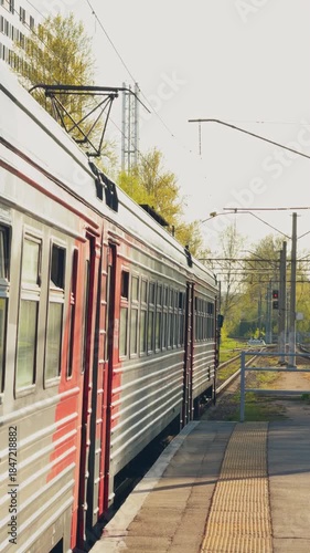 Russia, St.Petersburg, the electric train stops at the railway station, The passenger electric train goes nearby summer park, train of the Russian Railway company