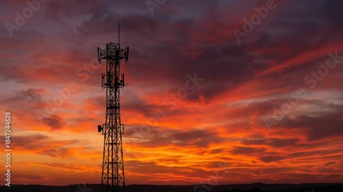Wallpaper Mural A lone cell tower stands in silhouette against a dramatic sunset sky painted with vibrant orange and red hues and wispy clouds Torontodigital.ca