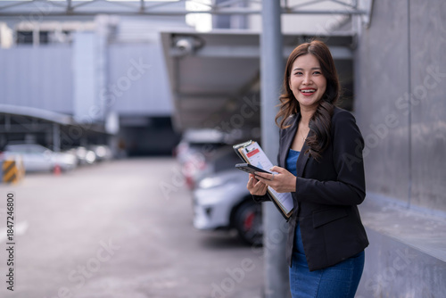 Asian businesswoman smiling holding clipboard and smartphone