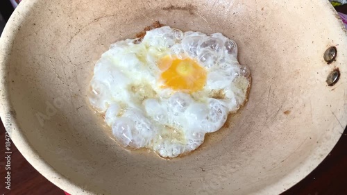 Sunny side up fried egg cooking in a hot wok or pan