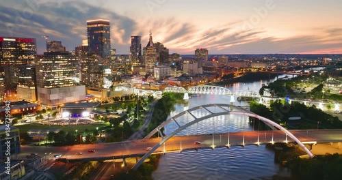 Driving cars on bridge highway near high-rise buildings in downtown district of Nashville, Tennessee, USA. American city with business financial district at sunset.